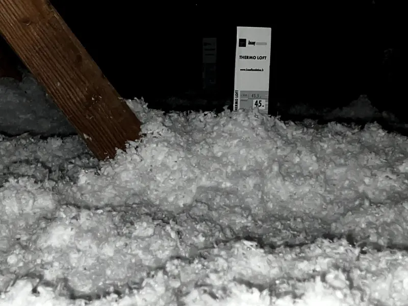 Isolant soufflé dans des combles avec règle de hauteur graduée
