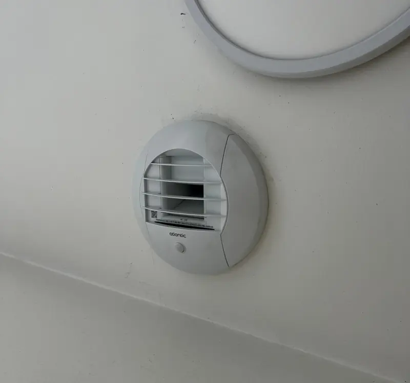 Bouche d'extraction de ventilation mécanique posée au mur d'une pièce humide